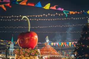 giant decorative apple on roof of stall on colorful new year fairground in downtown at night