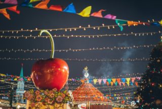 giant decorative apple on roof of stall on colorful new year fairground in downtown at night